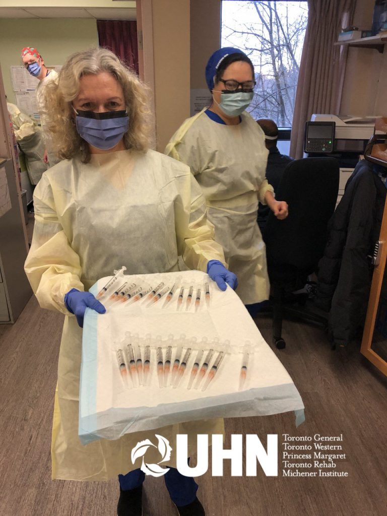 Toronto Western FHT staff in PPE holds a tray with vaccine