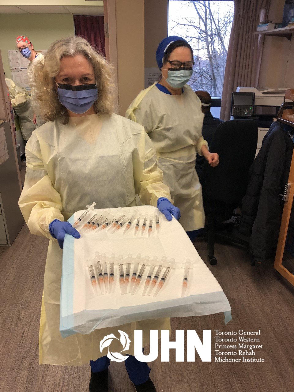 Toronto Western FHT staff in PPE holds a tray with vaccine