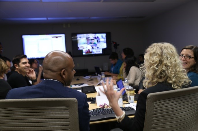 View frome behind of people in a meeting room with more light on those at the back