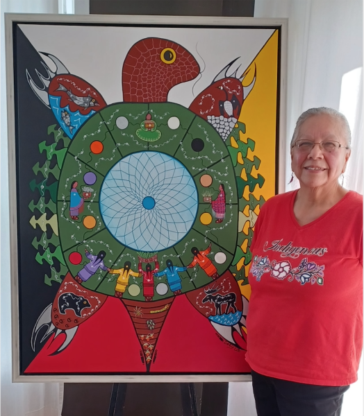 The artist Zoey Wood-Salomon stands to the right of her piece, a turtle with people on the circumference of its shell