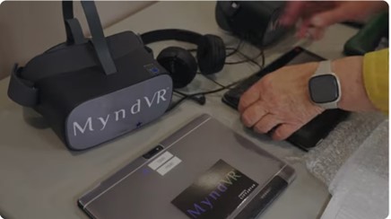 A pair of hands puts a VR headset and other equipment on a desk.